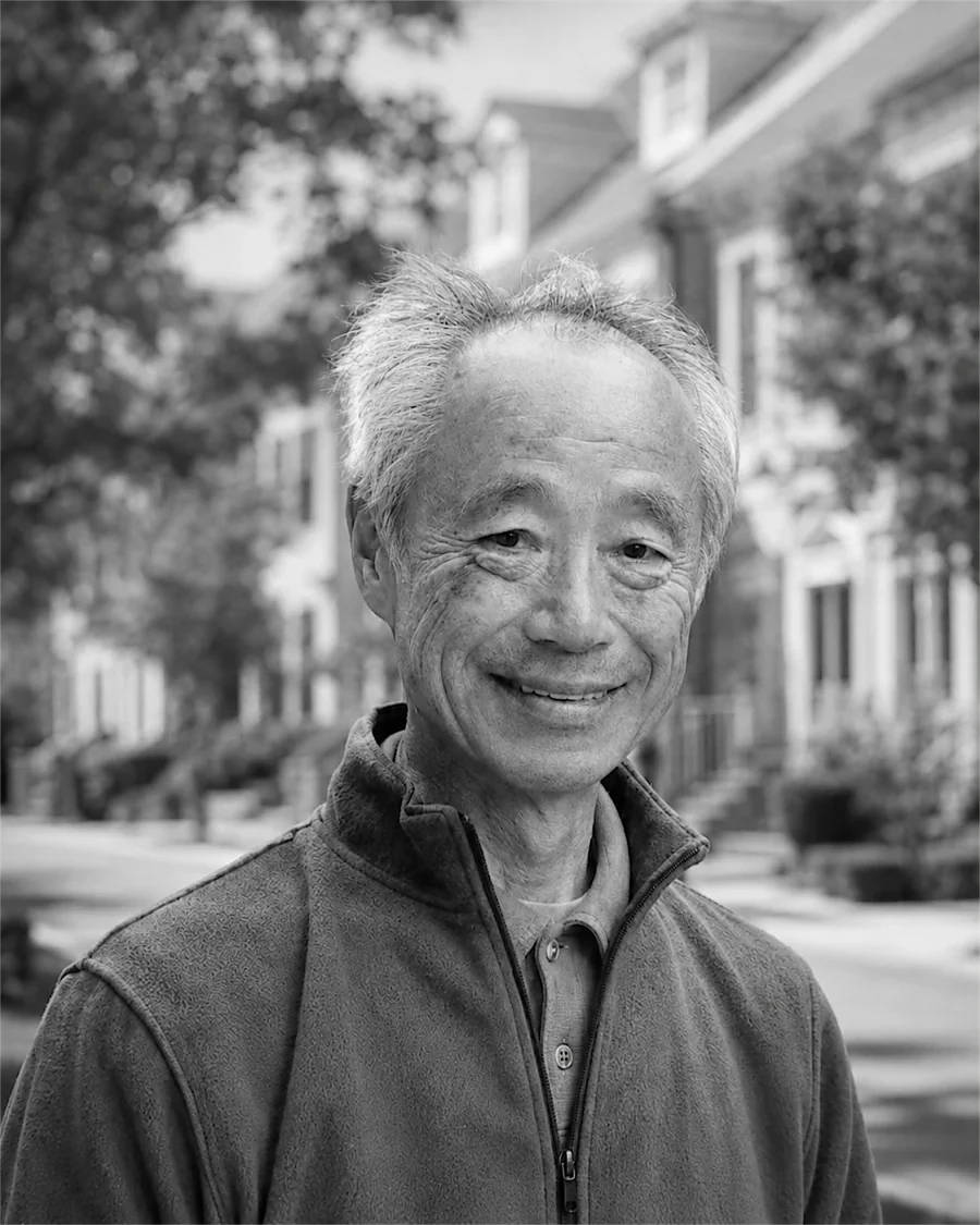 戸谷英世。米国の住宅地を背に立つ肖像